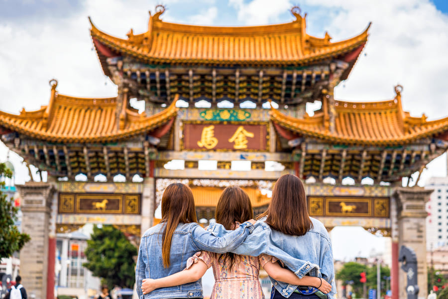 Vacaciones familiares en China: Tres personas contemplando un templo de arquitectura tradicional asiática durante un viaje turístico.