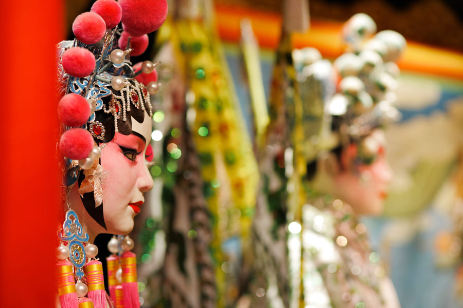 Primer plano de perfil de un maniquí o intérprete con el maquillaje tradicional y el elaborado tocado de la Ópera China